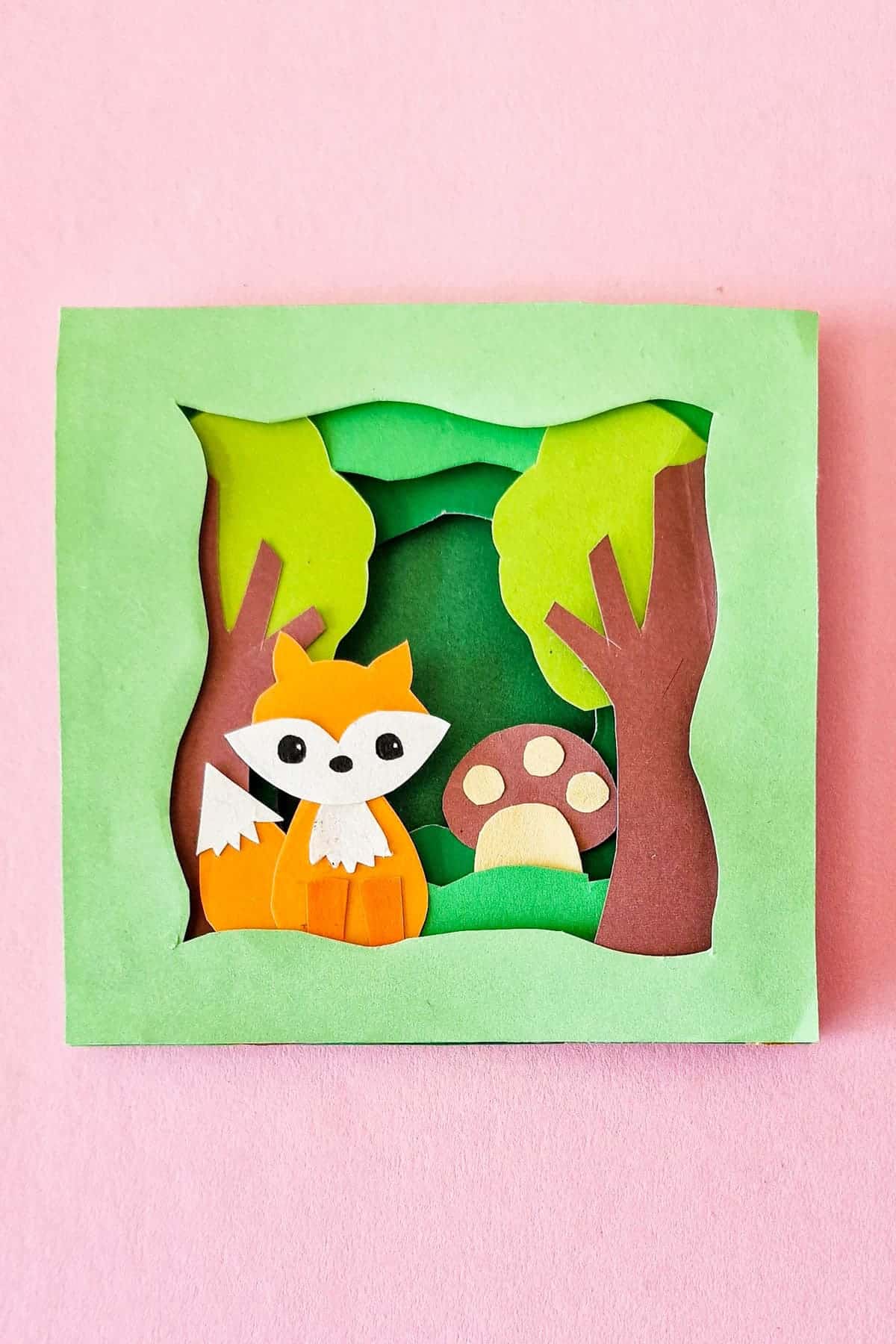 Layered green paper woodland scene with an orange fox and mushroom