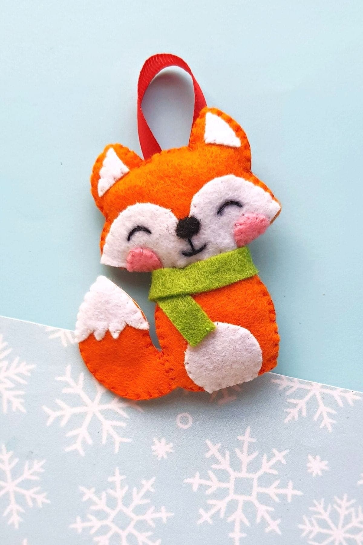 Orange felt fox ornament with a green scarf and ribbon loop